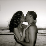 man and woman naked at ocean kissing